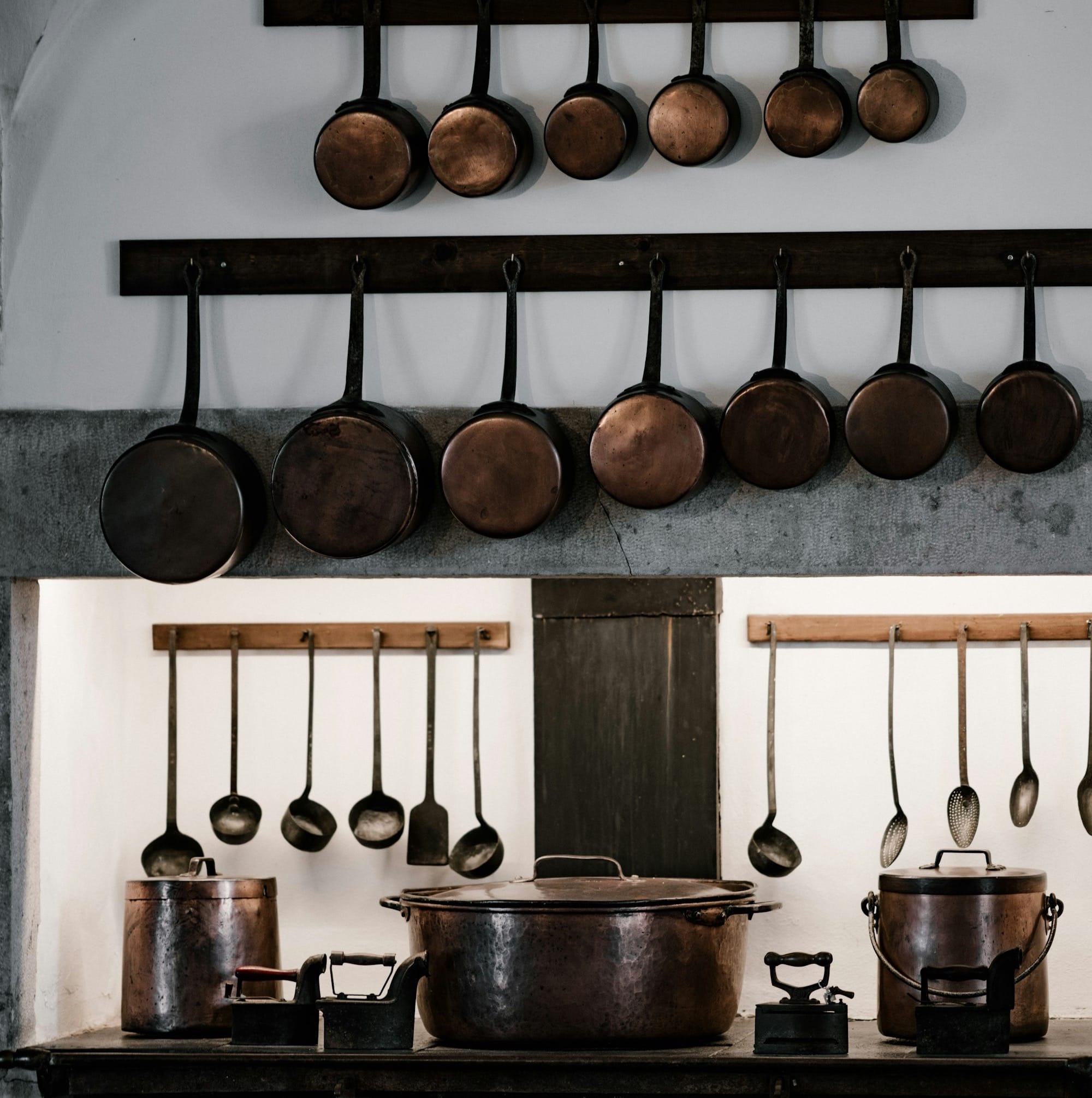 assorted cooking pots and pans hangs over black cast iron stove